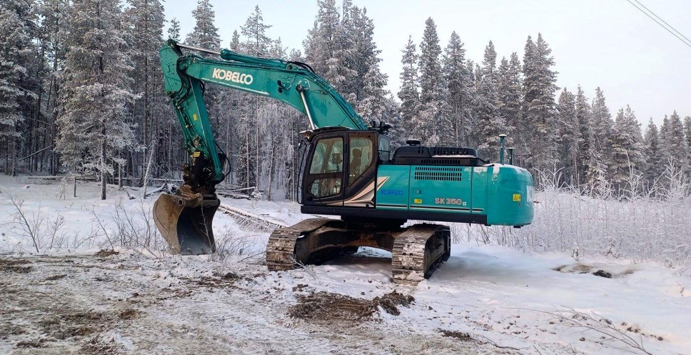 Levin Puskutöiden Kobelco-kaivinkone lumisessa metsässä
